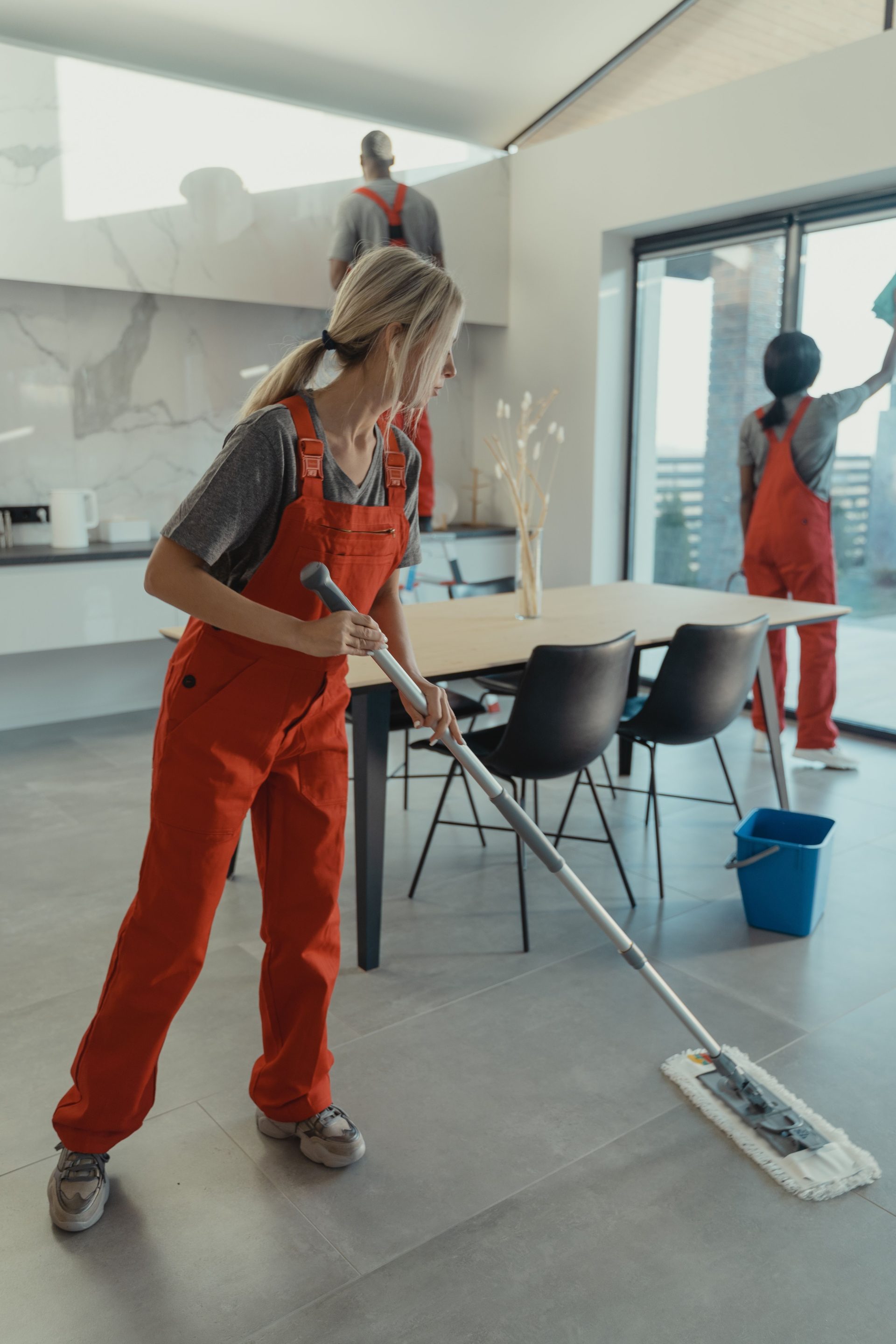 Reinigungsteam in roten Overalls wischt und desinfiziert das Innere eines modernen Hauses.